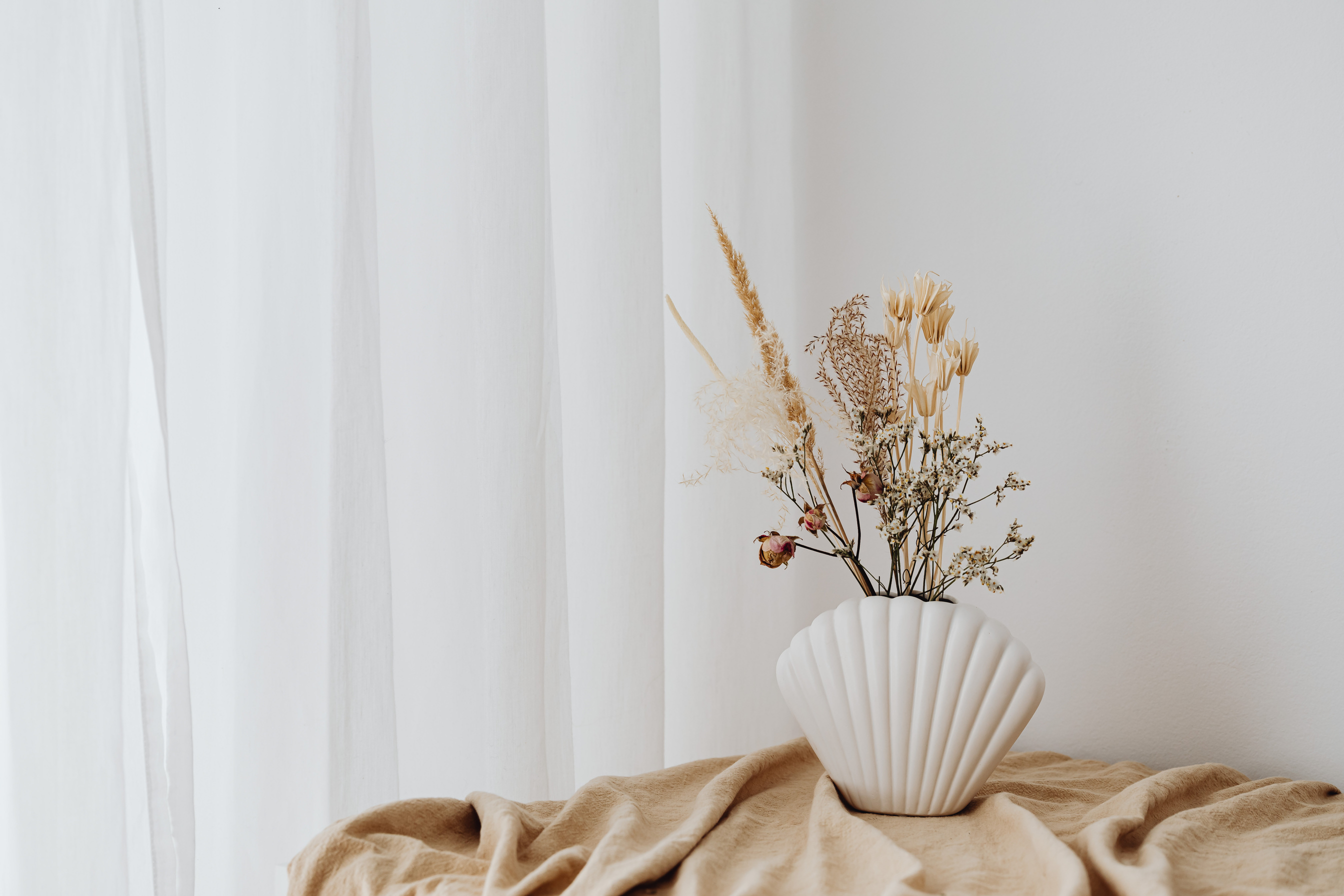 Flowers in White Ceramic Vase on Brown Textile